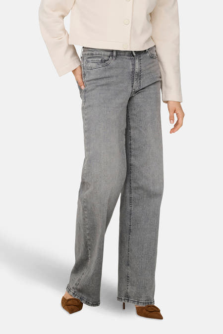 Jean wide bleu clair de JDY, associé à une blouse blanche et des chaussures marron.