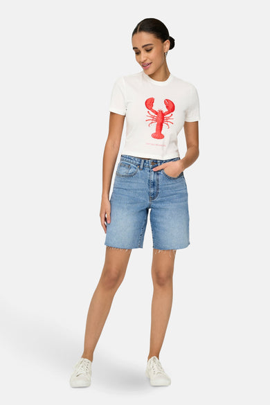 T-shirt blanc à manches courtes de ONLY, avec imprimé crabe rouge et associé à des bermudas denim et des baskets blanches.