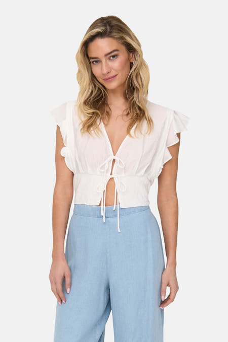 T-shirt sans manches de ONLY®, avec des plis et un détail de nœud, porté avec un pantalon bleu.
