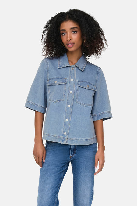 Chemise en jean bleu clair à manches courtes de ONLY, avec poches poitrine et portée avec un jean et des talons bleus.