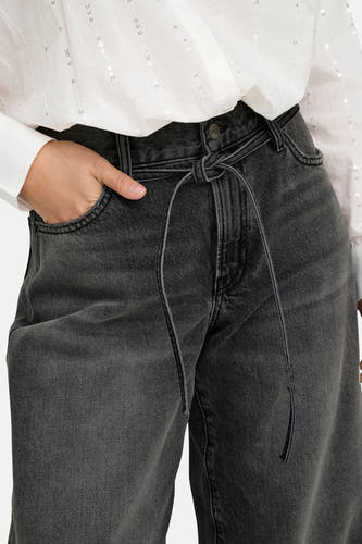 Jean droit gris anthracite d'ONLY, avec ceinture élastique et une main dans la poche, associé à un chemisier blanc brillant.