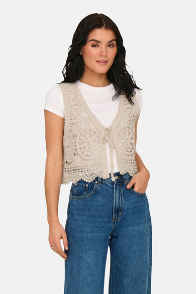Gilet écru de JDY avec des détails crochetés, porté sur un t-shirt blanc et un jean bleu.