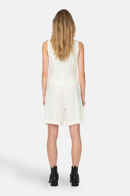 Blazer blanc de ONLY®, l'arrière du blazer est visible, avec des shorts coordonnés et des bottes noires.
