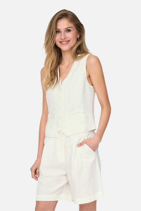 Blazer blanc d'ONLY, porté avec une short et un gilet par une femme souriante.