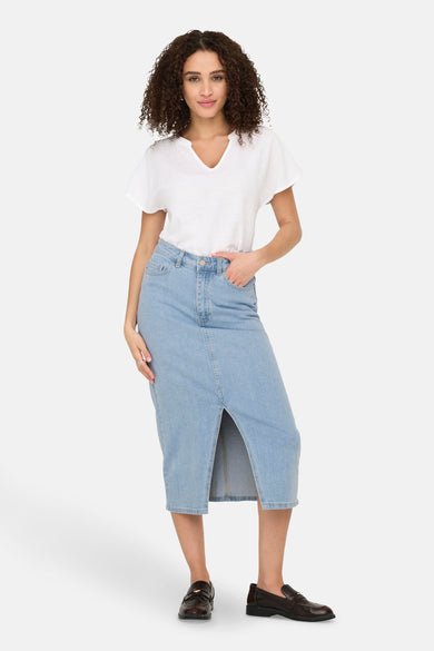 Lange lichtblauwe denim rok van JDY, met een split en gecombineerd met een wit T-shirt en bruine schoenen.