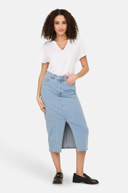 Lange lichtblauwe denim rok van JDY, met een split en gecombineerd met een wit T-shirt en bruine schoenen.