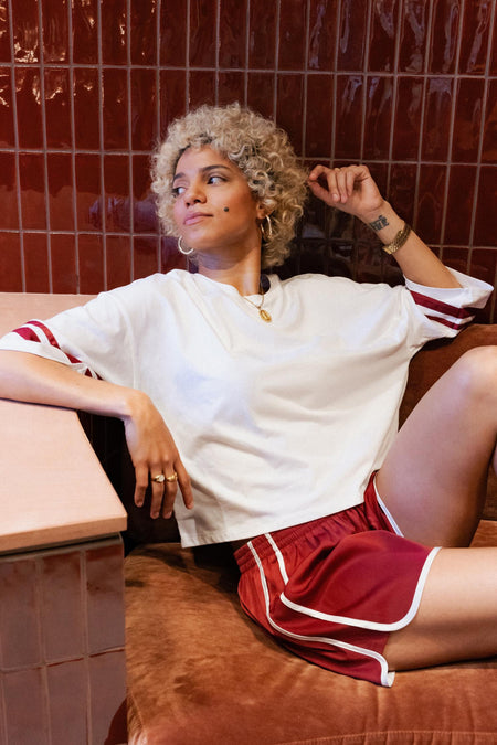 Short rouge ONLY®, avec des accents blancs et porté par une femme en chemise blanche.