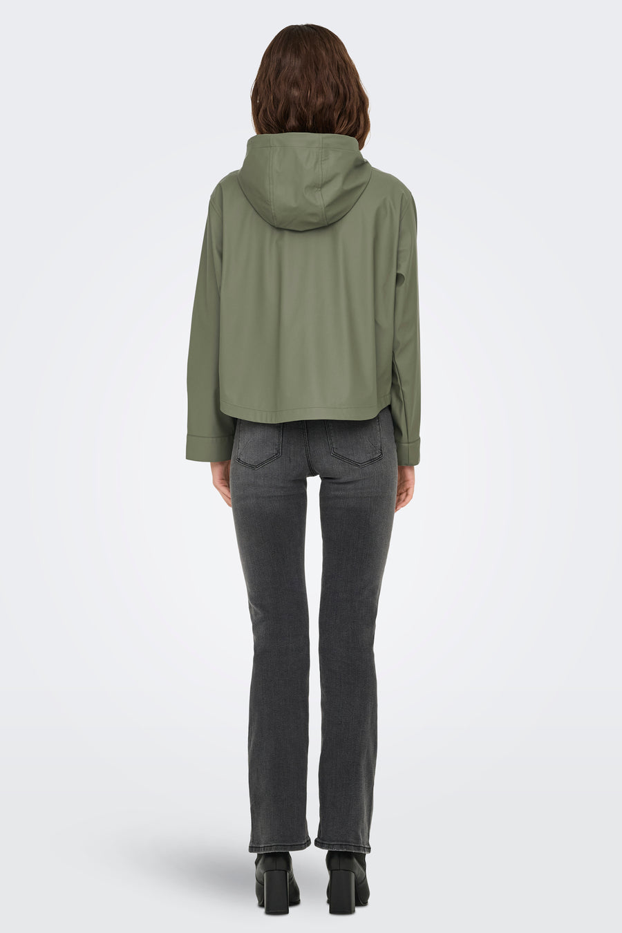 Kaki de pluie ONLY, avec un capuchon, associé à un jean gris et des bottes noires.