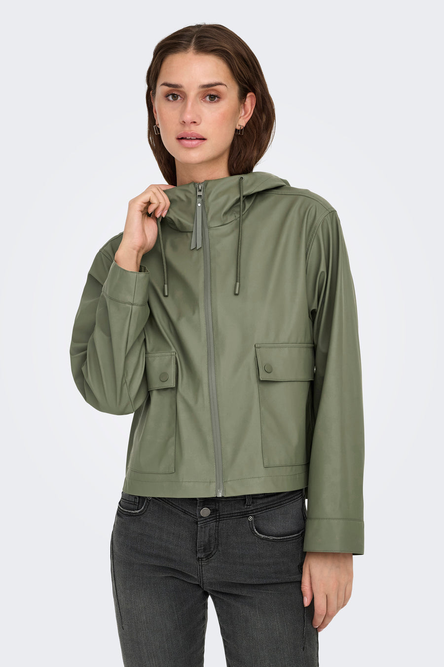 Veste de pluie multicolore ONLY ONLY avec capuche, poches avec fermeture à bouton et portée sur un jean foncé.