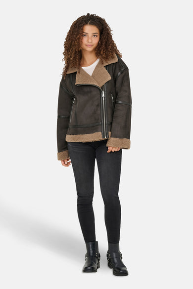 Manteau court brun d'ONLY, avec une doublure en fourrure de teddy, porté avec des jeans noirs et des bottes.