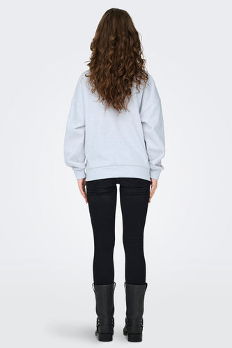 Achterkant van een vrouw in een grijze sweater, zwarte broek en zwarte laarzen.