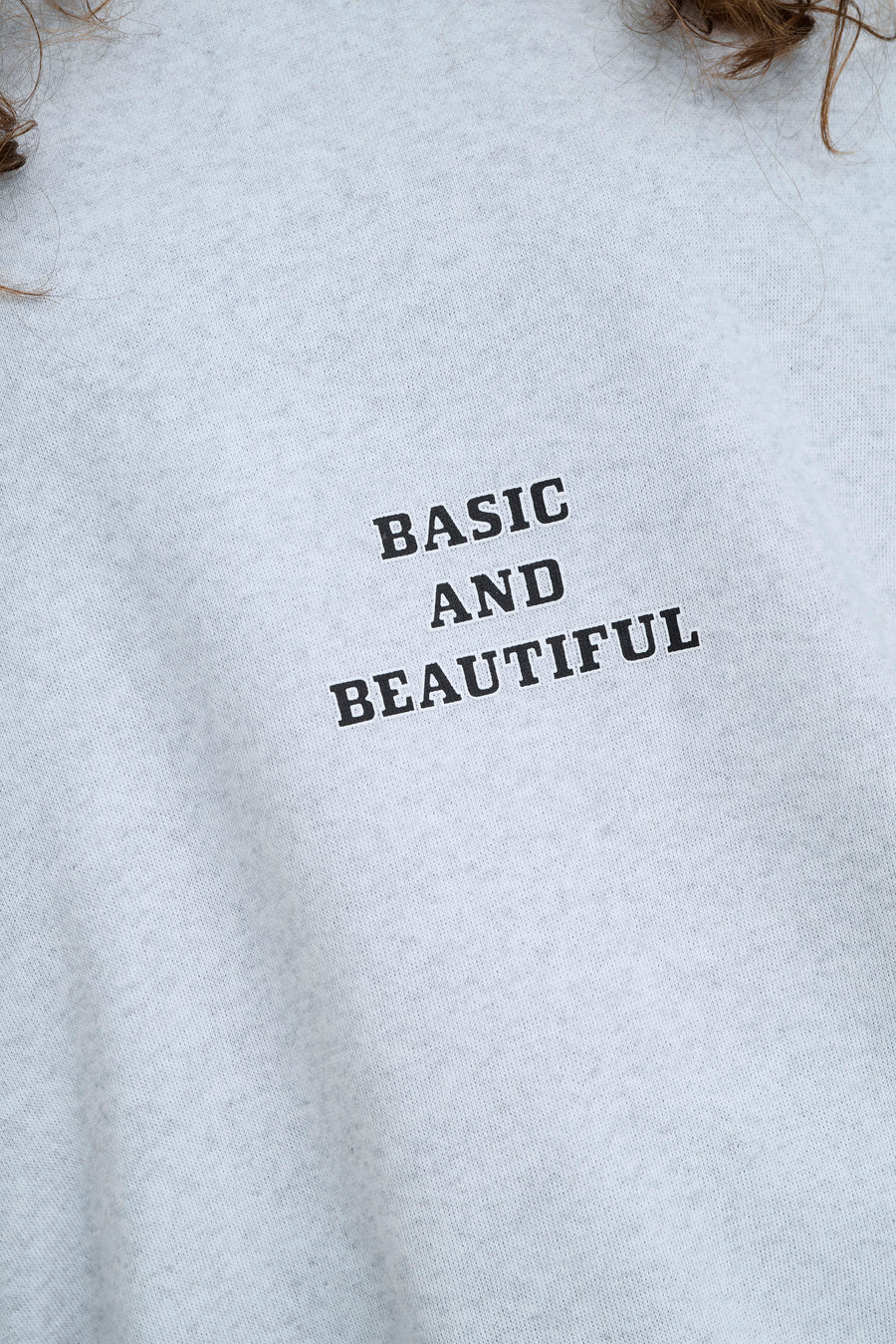 Grijze sweater met zwarte tekst "BASIC AND BEAUTIFUL".