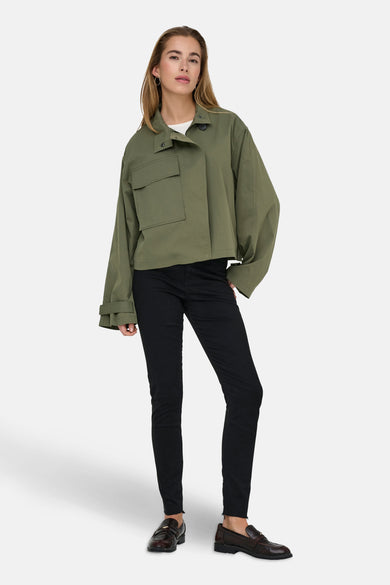 Veste courte verte de ONLY, avec des manches longues, portée sur un t-shirt blanc et un pantalon noir.
