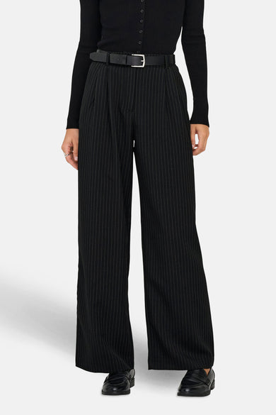 Pantalon noir de ONLY, avec une rayure blanche et des jambes larges, associé à un haut noir et des chaussures noires.