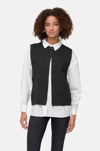 Veste à manches courtes grise d'ONLY, portée sur une chemise blanche avec des jeans foncés et des bottes noires.