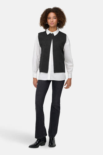 Grijs mouwloos vest van ONLY, gedragen over een wit overhemd met donkere jeans en zwarte laarzen.
