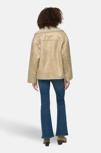 Mauve manteau court d'ONLY, avec un col en fourrure de lama et porté avec un jean bleu.