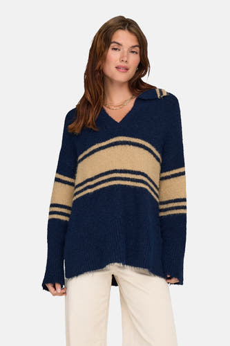 T-shirt bleu ONLY® avec des rayures beige, porté avec un pantalon blanc et des bottes brunes.