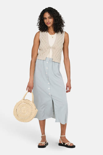 Veste écru de ONLY®, avec un motif évasé, portée sur une chemise blanche et une jupe bleu clair.