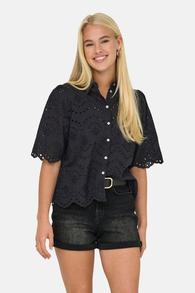 Chemise noire à manches courtes ONLY, avec détails brodés et portée avec un short en jean noir et une ceinture.