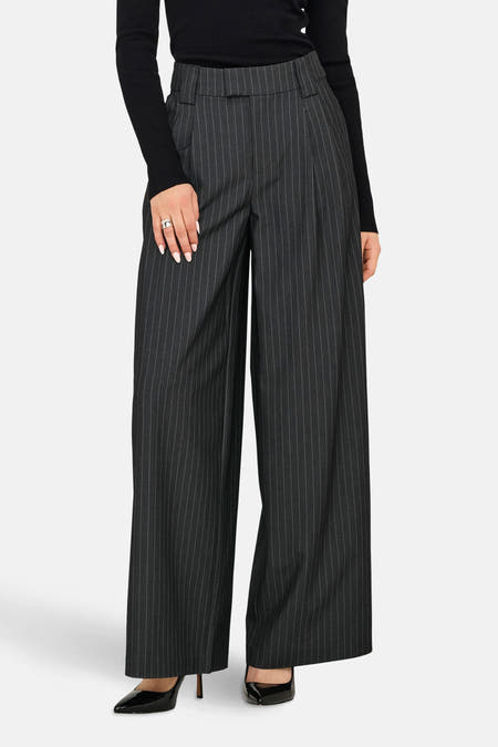 Pantalon gris ONLY® avec une rayure blanche, associé à un haut noir et des bottes.
