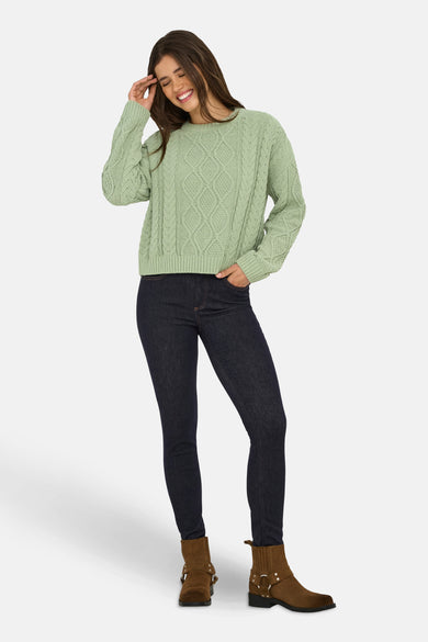 T-shirt vert de ONLY® avec un col rond, un motif côtelé et porté avec des jeans foncés et des bottes brunes.