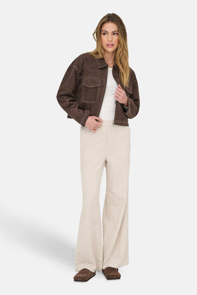 Manteau court brun d'ONLY®, avec des boutons contrastants et porté sur un chemisier blanc et un pantalon beige.