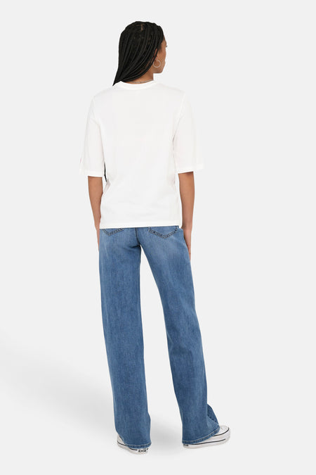 T-shirt blanc à manches courtes d'ONLY, avec une encolure simple, associé à des jeans larges et des baskets basses.