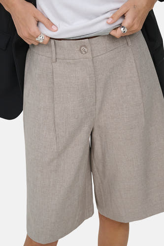 Short beige de ONLY® avec texture légère, plis et fermeture à boutons, porté avec un haut blanc et un blazer noir.