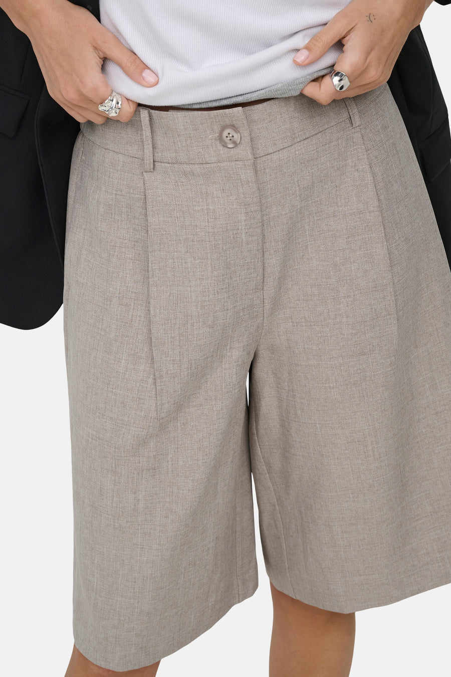 Short beige de ONLY® avec texture légère, plis et fermeture à boutons, porté avec un haut blanc et un blazer noir.