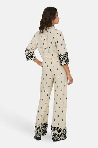 Pantalon écru de JDY, avec des motifs de feuilles noires sur les poches et de petites impressions de feuilles.