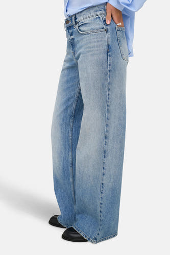 Jean en denim bleu clair large de ONLY, avec un chemisier bleu et des chaussures noires.