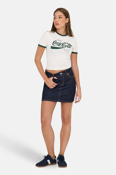 Jupe courte denim bleu marine de ONLY, associée à un T-shirt blanc avec logo et des baskets bleues.
