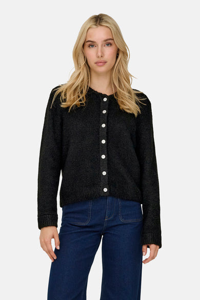 Cardigan noir d'ONLY, avec des manches longues et des boutons blancs, associé à des jeans bleu marine.