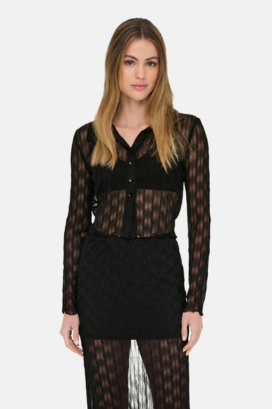 T-shirt noir à manches longues de ONLY, avec un motif transparent et tissé, porté avec un soutien-gorge noir et une jupe.