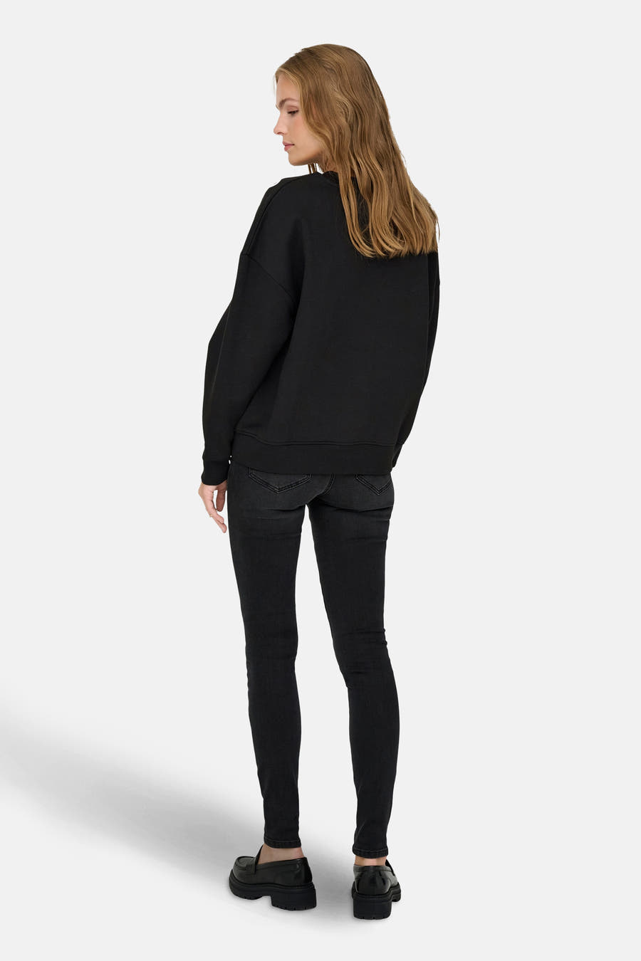 Zwarte sweater van JDY, met lange mouwen, gecombineerd met een zwarte jeans en zwarte loafers.