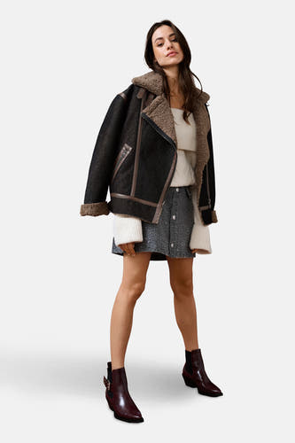 Manteau de denim bleu marine court d'ONLY, avec des accents marrons et un col en laine, associé à une jupe et des bottines.