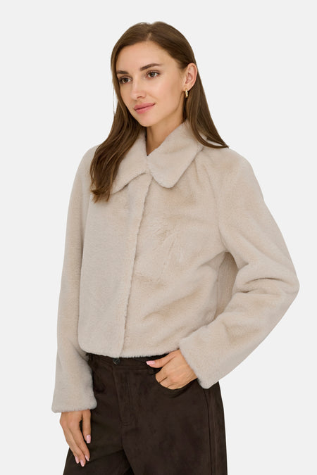 Manteau en fausse fourrure gris clair avec col montant de JDY, texture douce, modèle de profil latéral, pantalon foncé, main dans la poche