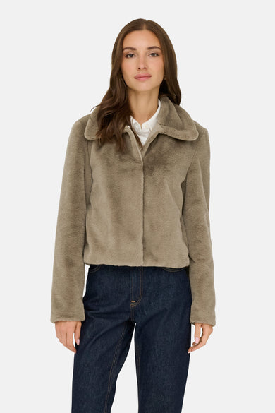 Manteau court beige de JDY, porté sur une chemise blanche et un pantalon de travail foncé.