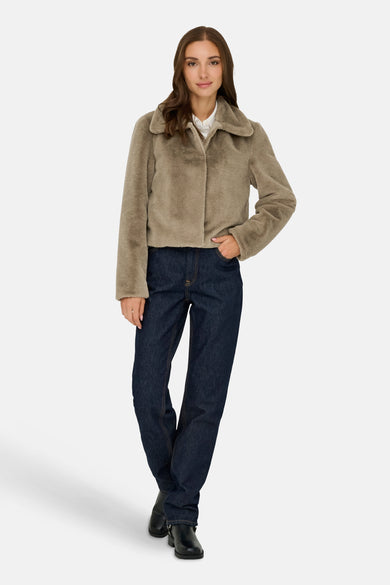 Manteau court beige de JDY, porté avec un chemisier blanc et des jeans bleu marine.