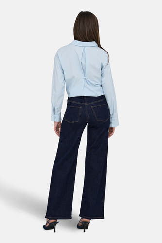 Jean bleu marine droit de JDY, avec des boutons et associé à une chemise bleue claire et des baskets.