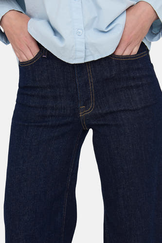 Jean droit bleu marine de JDY, avec les mains dans les poches et une chemise bleue claire.