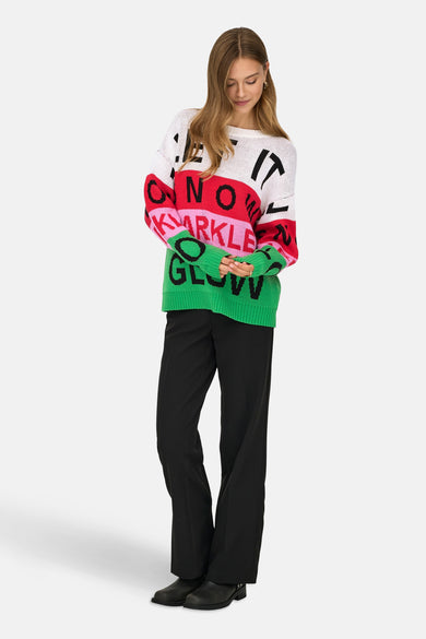 Multikleurige trui met ronde hals van ONLY, met de tekst "One It No Sparkle Glow", gecombineerd met zwarte broek en laarzen.
