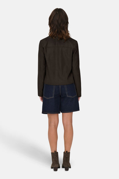 Manteau court brun de JDY, avec un motif uni, porté avec des shorts en denim et des bottes brunes.