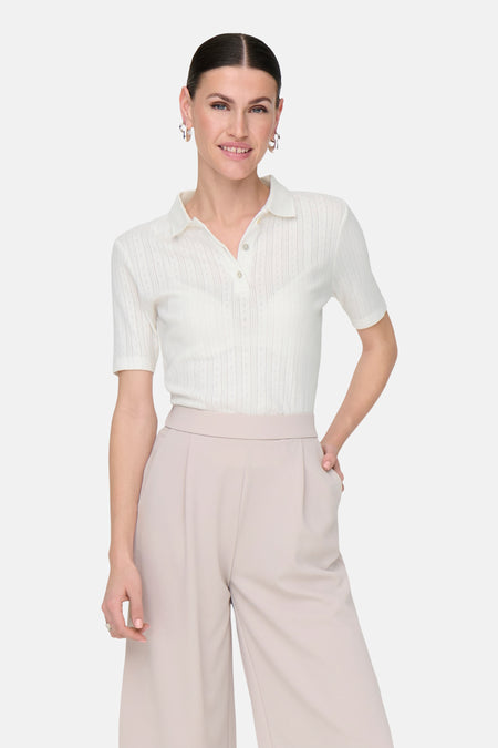 Polo blanc à manches courtes de JDY, avec un motif finement structuré, porté avec un pantalon beige large.