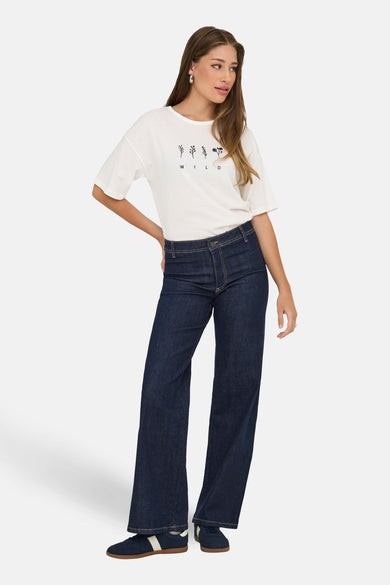Jean bleu marine droit de JDY, associé à un T-shirt blanc imprimé et des baskets bleues.