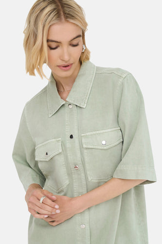Vrouw in groene blouse met korte mouwen en zilveren ring.
