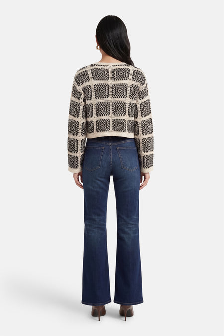 Multikleurig vest van ONLY®, met een zwart-wit geometrisch patroon, gecombineerd met donkerblauwe jeans en bruine hakken, achteraanzicht.
