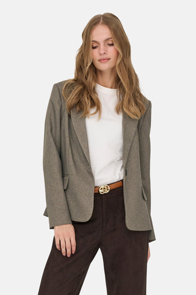 Blazer marron de JDY, avec une fermeture à un seul bouton et des poches brodées, porté sur un chemisier blanc avec un pantalon marron foncé.