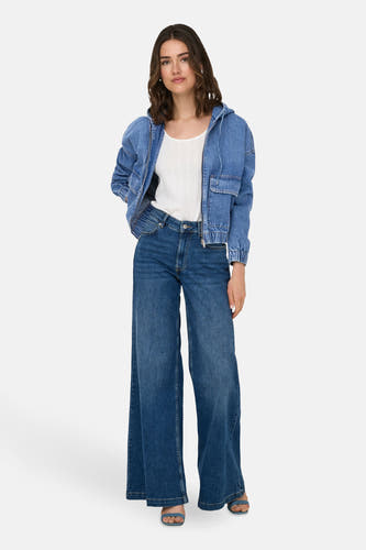Jean en denim bleu marine moyen, ONLY, avec fermeture à glissière et poches, associé à une chemise blanche et des jeans larges.
